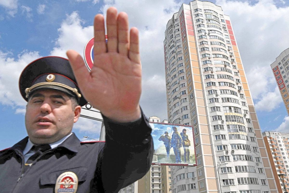 شرطي روسي يمنع التصوير في مبنى أصيب بهجوم المسيّرات في موسكو (أ ف ب)