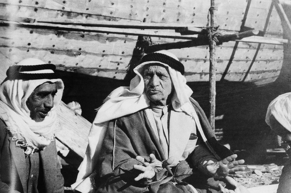 شيخ القلاليف أحمد الاستاد جالساً بجانب سفينة من صناعته