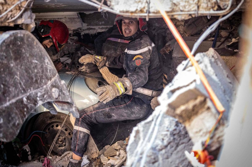 منقذان يحاولان الوصول إلى محاصرين تحت أنقاض منزل تهدم في قرية بناحية الحوز قرب مراكش أمس (أ ف ب)