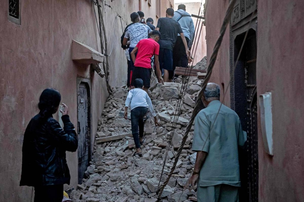 سكان بين الدمار في أحد شوارع المدينة القديمة في مراكش (أ ف ب) 
