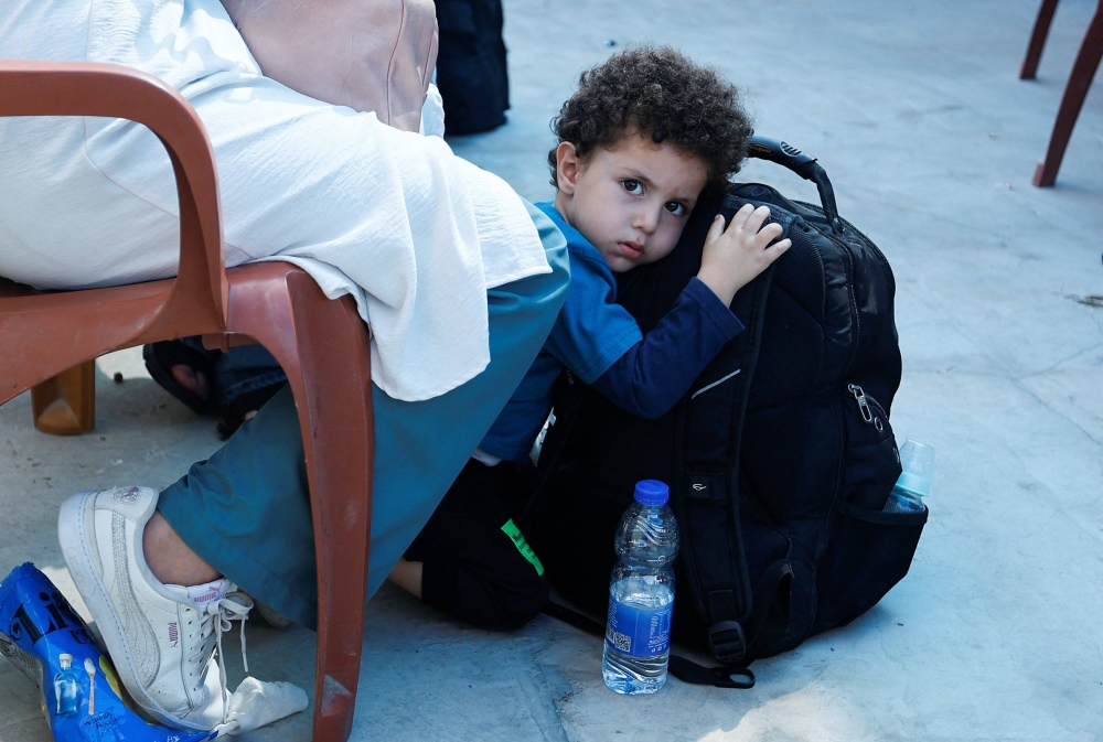 صبي ينظر بينما ينتظر الفلسطينيون ذوو الجنسية المزدوجة خارج معبر رفح الحدودي مع مصر على أمل الحصول على إذن لمغادرة غزة