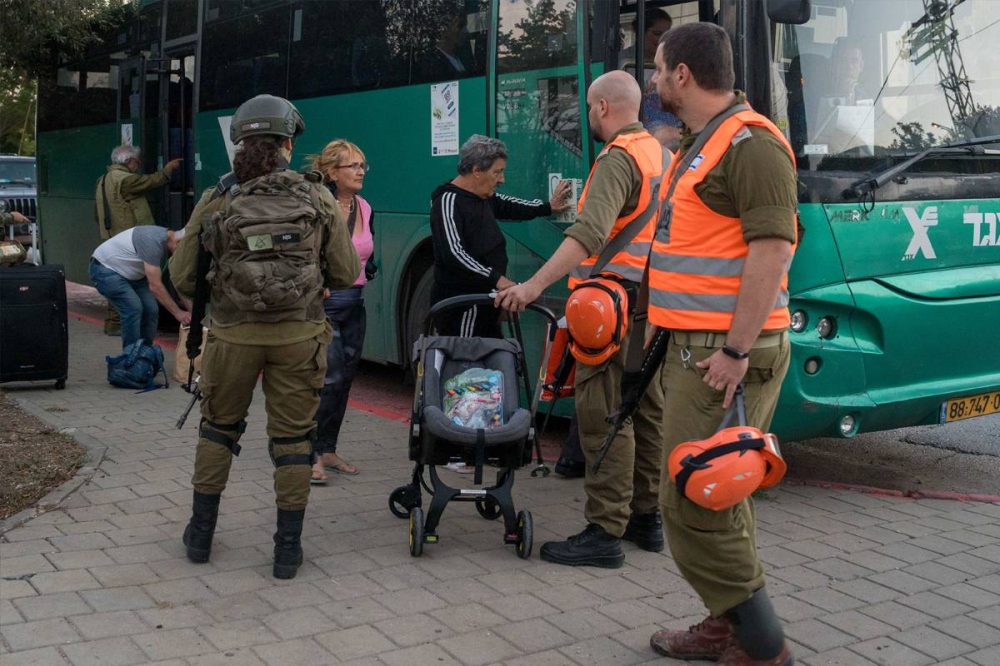إسرائيليون يستعدون لركوب حافلة مخصصة لنقلهم خارج مستوطنة كريات شمونة المحاذية لجنوب لبنان أمس (شينخوا)