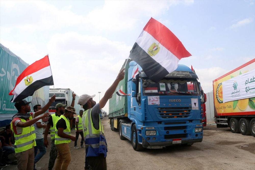 عمال شاحنات تحمل مساعدات إغاثية على الجانب المصري من معبر رفح أمس (أ ف ب)
