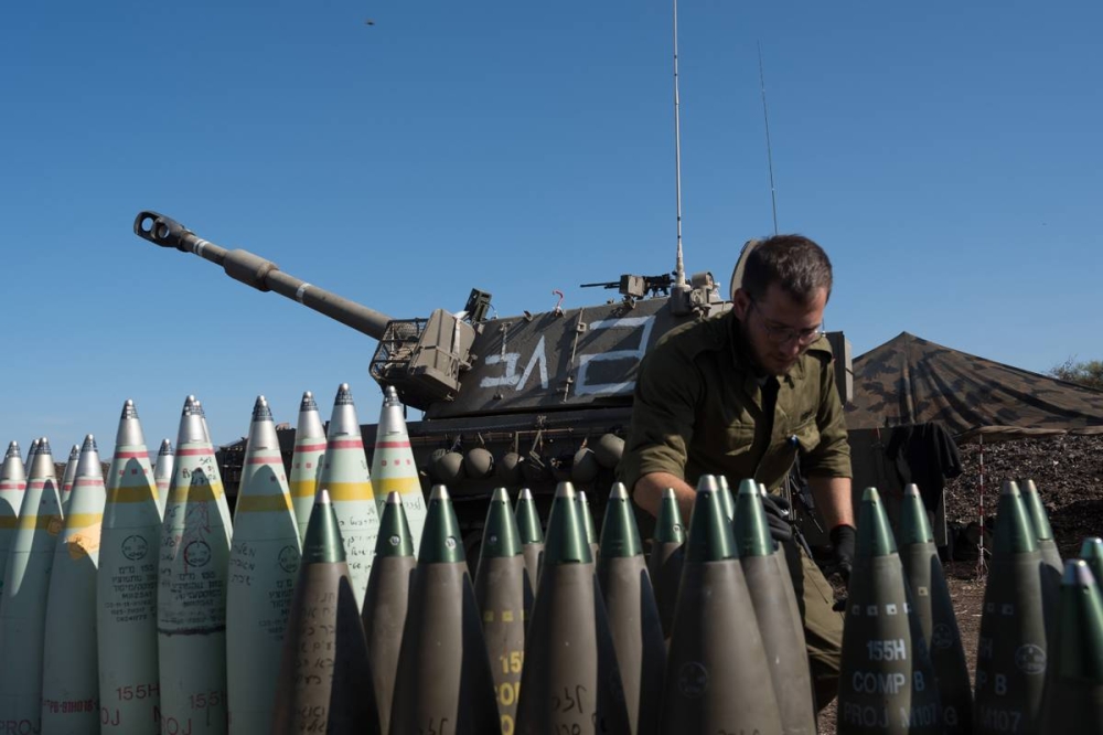 جندي إسرائيلي يجهز قذائف بجوار دبابة قرب السياج الحدودي اللبناني أمس (شينخوا)