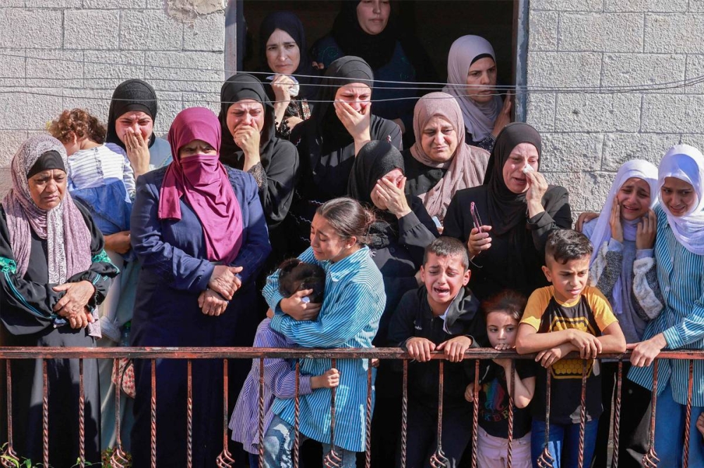 نساء وأطفال خلال تشييع جثمان مسن فلسطيني قتلته القوات الإسرائيلية في الضفة الغربية المحتلة أمس (أ ف ب)