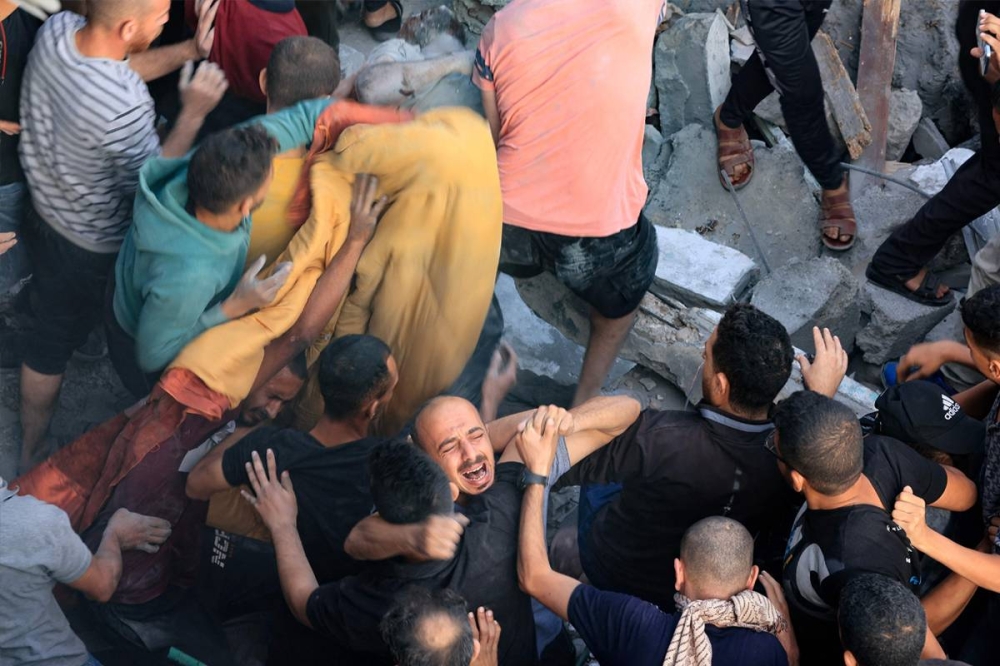 فلسطيني يبكي خلال انتشال شقيقه من تحت الأنقاض في مخيم المغازي (أ ف ب)