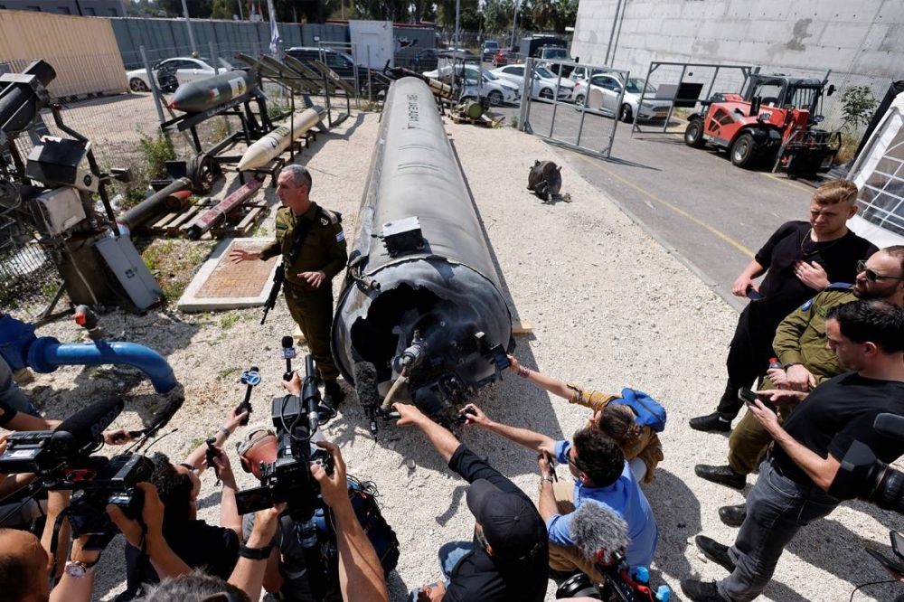 متحدث باسم الجيش الإسرائيلي خلال مؤتمر، أمس، بجوار هيكل صاروخ قال إنه تم انتشاله من البحر الميت عقب هجوم إيران على قاعدة بجنوب إسرائيل (رويترز)