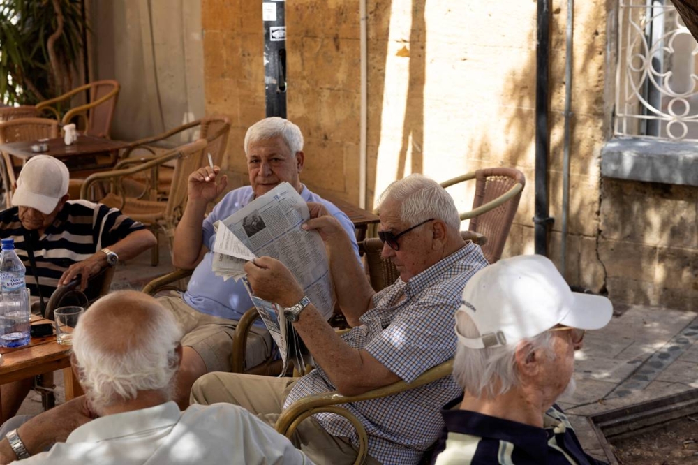 قبارصة في مقهى أمام كنيسة باناجيا فانيروميني بنيقوسيا أمس (رويترز)