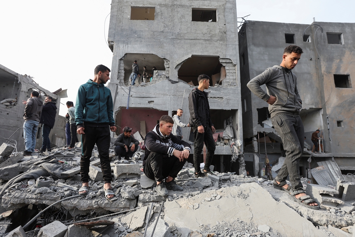 فلسطينيون بمحيط منازل مدمرة جراء غارات إسرائيلية على مخيم النصيرات وسط غزة (رويترز)