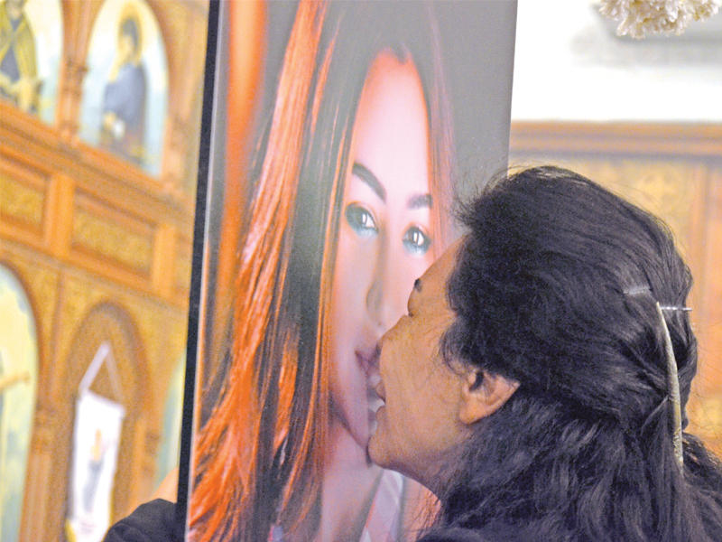 والدة المضيفة يارا الهاني (25 عاماً) التي قضت بتحطم الطائرة تقبل صورتها في كنيسة بالقاهرة أمس 