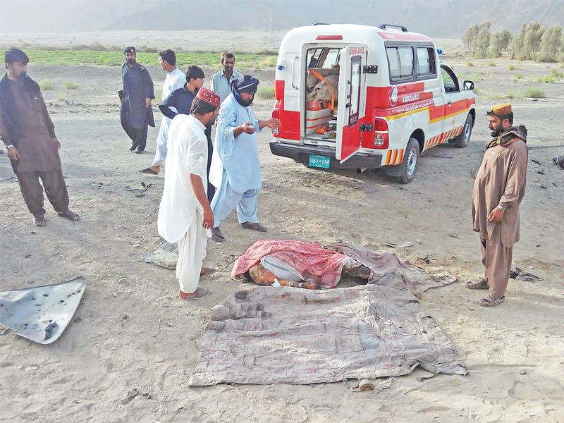باكستانيون يتجمعون حول جثة مجهولة الهوية بجانب مركبة دمرت بضربة جوية أميركية يعتقد أنها الغارة التي قتل فيها منصور أمس الأول 
