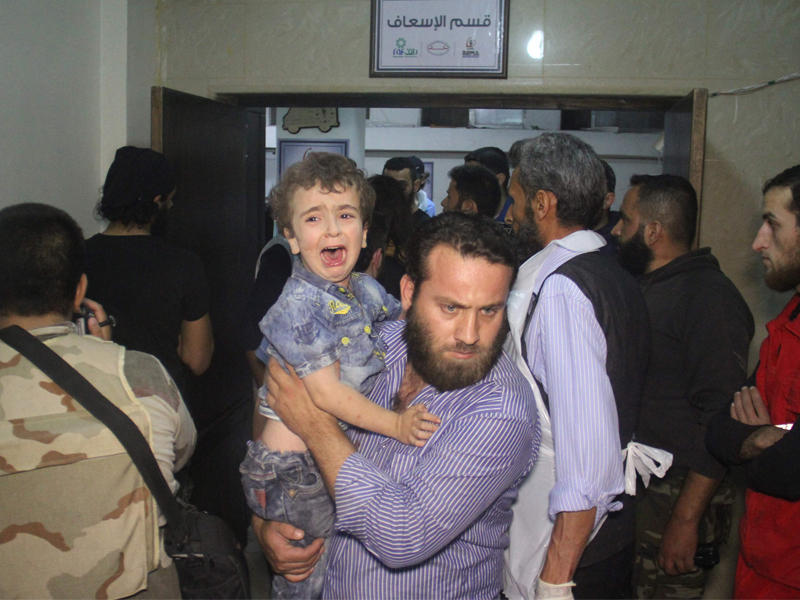 سوري يحمل طفله داخل مشفى المدينة