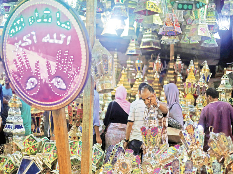 مصري يعاين «فانوس رمضان» داخل سرادق في حي السيدة زينب جنوب القاهرة أمس الأول (رويترز)