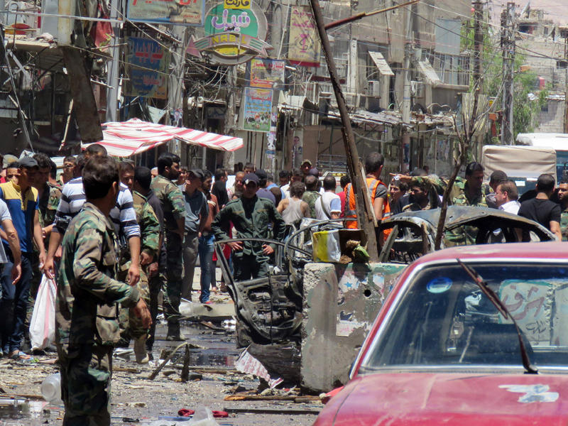 جنود ومقاتلون يتفقدون موقع التفجير المزدوج خارج مزار السيدة زينب جنوب دمشق