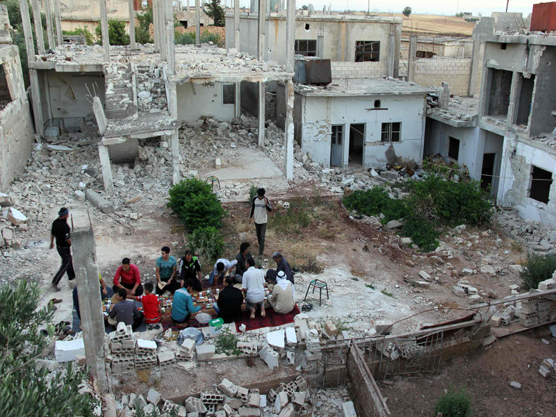 سوريون يستعدون لتناول الإفطار أمس الأول وسط مبانٍ دمرها النظام في تيرمعلة شمال حمص (أ ف ب)