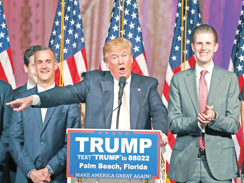 ترامب متوسطاً ابنه أريك (يمين) ومدير حملته المقال في مارس الماضي (أرشيف)