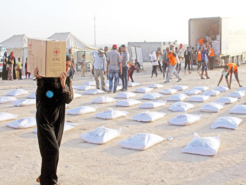 «الهلال الأحمر» العراقية توزع مواد غذائية على النازحين في الحبانية قرب الرمادي أمس الأول (أ ف ب)