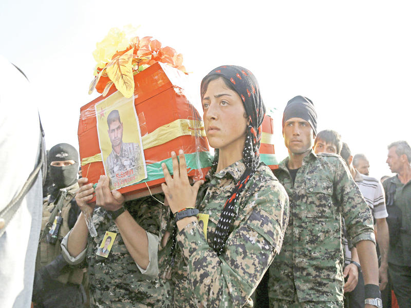 كردية تشارك في حمل نعش زميل لها قتل مع سبعة آخرين في المواجهة مع «داعش» بمنبج أمس الأول (أ ف ب)