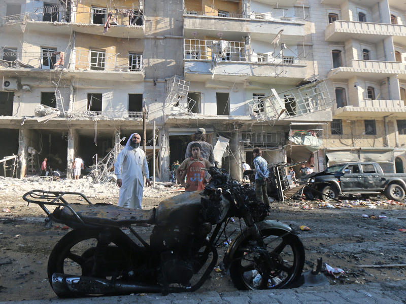 سوريون يتفقدون موقع الغارات على منطقة طارق الباب في حلب