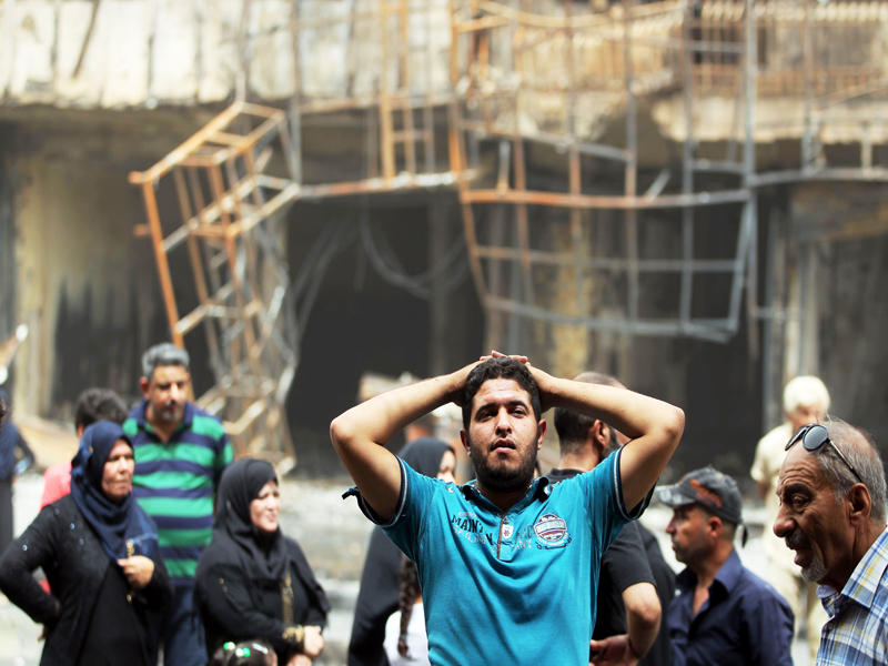 عراقيون يتفقدون مكان التفجير في الكرادة وسط بغداد أمس  (أ ف ب)