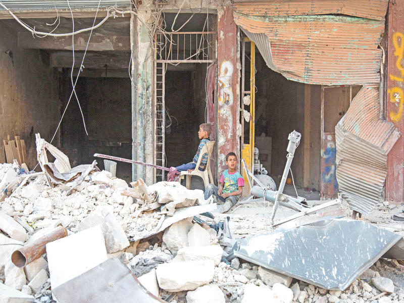 صبيان سوريان يجلسان وسط أنقاض مبنى دمره النظام في حي طارق باب بحلب أمس الأول (أ ف ب)