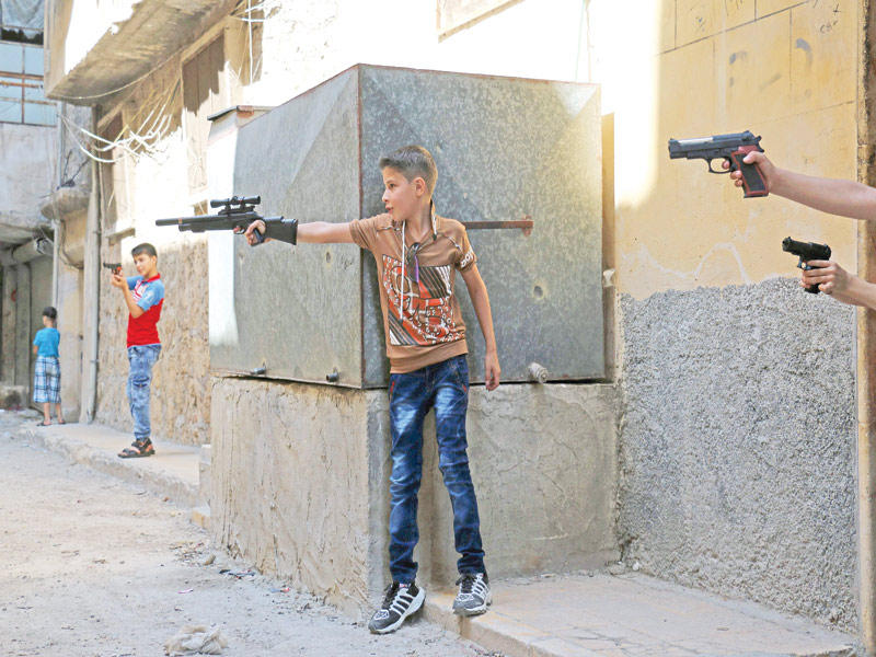 فتية سوريون يلهون بالأسلحة البلاستيكية في أحد أحياء حلب الشرقية أمس الأول (أ ف ب)n