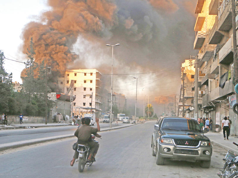 دخان الغارات النظامية يحجب الشمس عن حي الصالحين في حلب أمس (أ ف ب)
