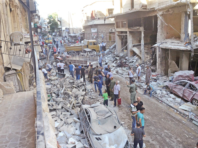 موالون يتفقدون أثار قصف المعارضة لغرب حلب أمس (رويترز) 