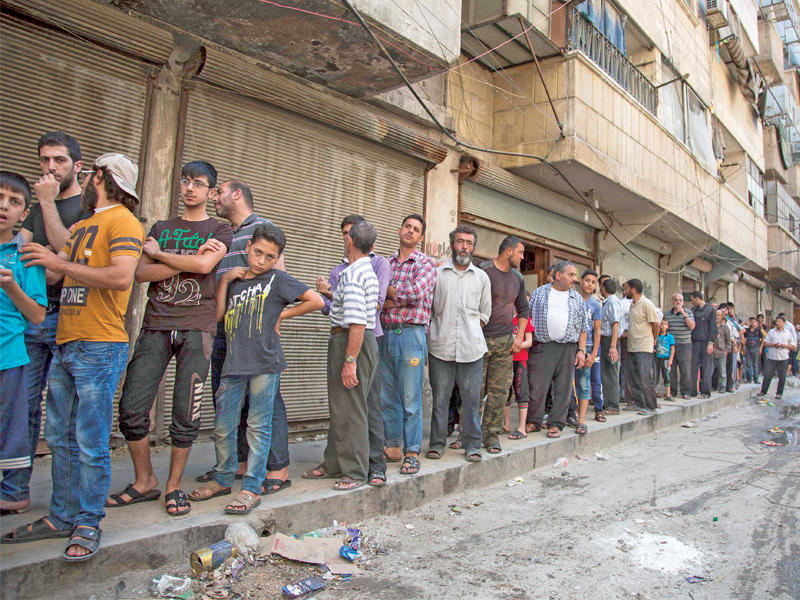 سوريون يصطفون لشراء الخبز في أحد أحياء حلب الشرقية أمس الأول (أ ف ب)