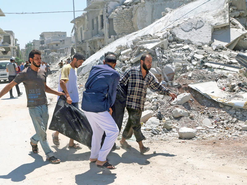 سوريون يجلون قتيلاً في غارة نظامية على حي الحلوانية شرق حلب أمس (رويترز)