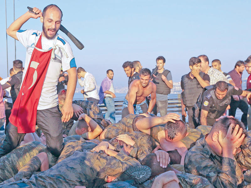 مدني يجلد جنوداً انقلابيين على جسر البوسفور في إسطنبول فجر أمس (رويترز)