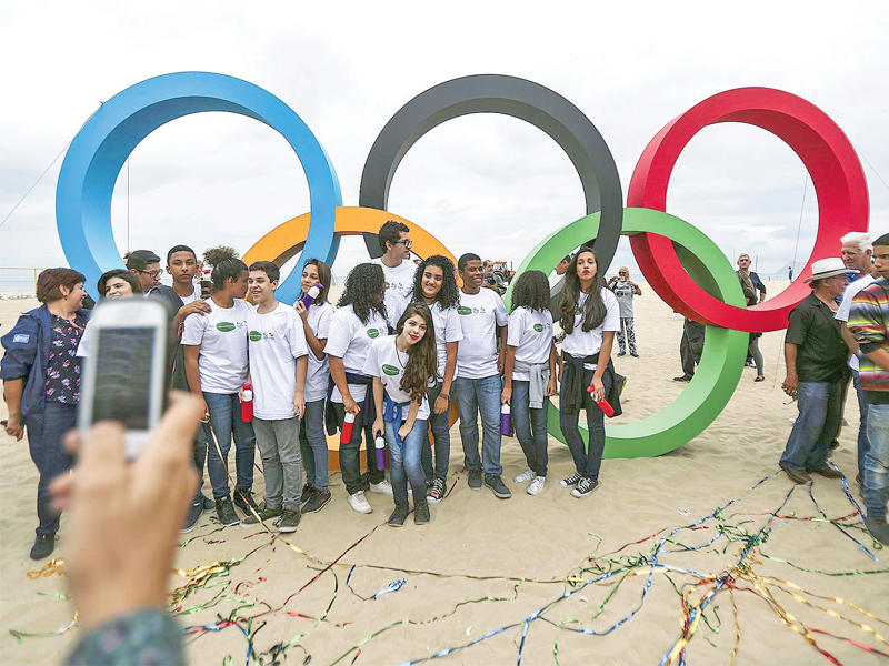 شبان برازيليون يأخذون صورة إلى جانب شعار الألعاب الأولمبية في ريو أمس 