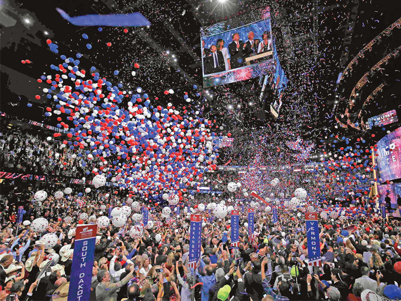 آلاف البالونات تنهمر على القاعة التي عقد فيها مؤتمر الجمهوريين في كليفلاند، ويبدو ترامب وعائلته إلى جانب نائبه المحتمل وزوجته على شاشة عملاقة يراقبون البالونات في ختام المؤتمر مساء أمس الأول  (رويترز)