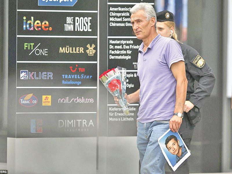 والد أحد الشبان الكوسوفيين الذين قتلوا في الهجوم يحمل صورته خلال توجهه لوضع الزهور في مكان المجزرة أمس  (رويترز)