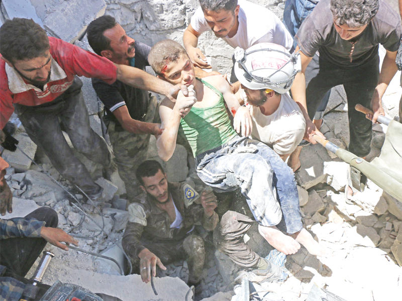 عناصر من الدفاع المدني يحملون طفلا بعد غارة جوية شمال حلب أمس  ( أ ف ب)