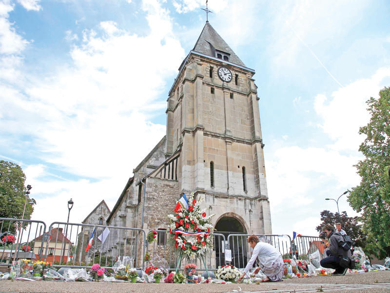 امرأة تضع زهوراً امام كنيسة سانت اتيان دو روفريه أمس (رويترز)