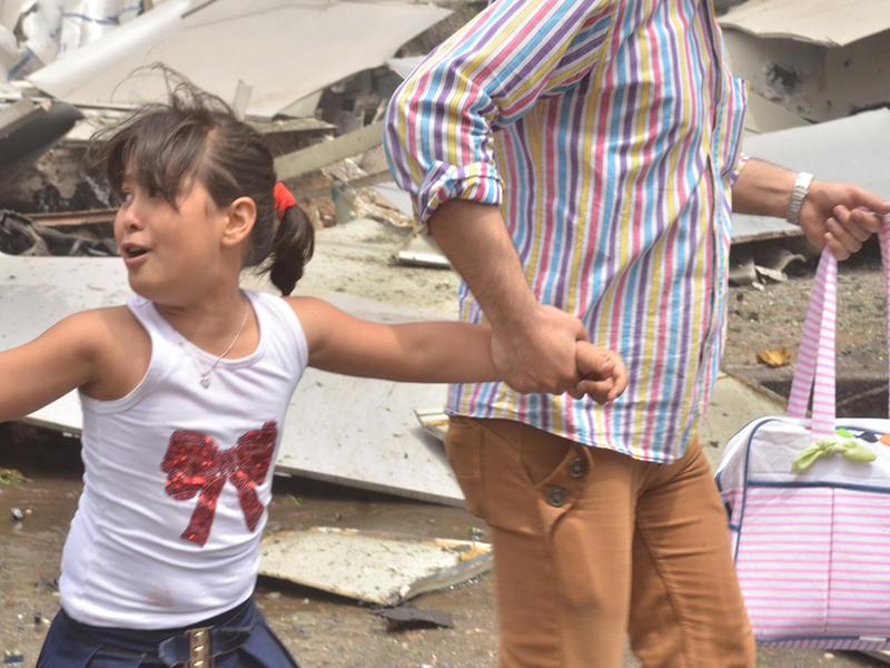 طفلة تفر مع والدها من موقع الغارات في حيهم بحلب قبل 4 أيام