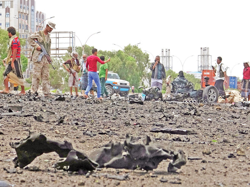 يمنيون عسكريون ومدنيون في موقع انفجار سيارة مفخخة استهدفت آلية للتحالف العربي في عدن أمس (رويترز)