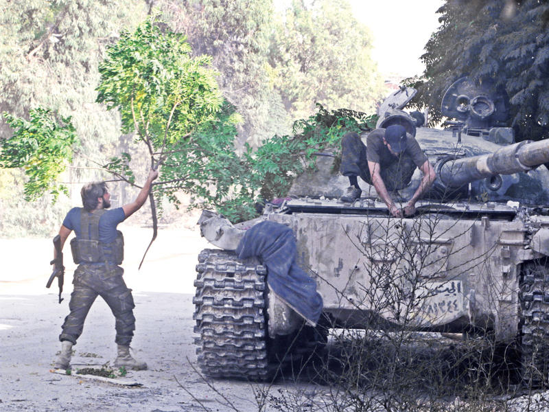 مقاتلان يغطيان دبابة بفروع الشجر لإخفائها عن طيران النظام في الراموسة جنوب غرب حلب أمس الأول        (رويترز)