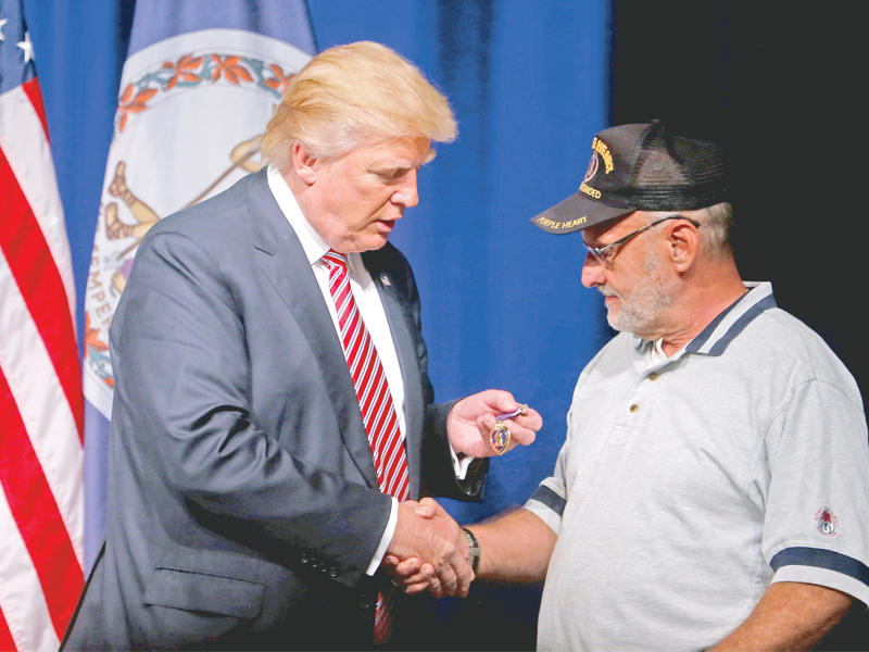 ترامب يحمل وساماً قدمه إليه مقاتل أميركي سابق خلال تجمع انتحابي في فرجينيا أمس الأولt(أ ف ب)