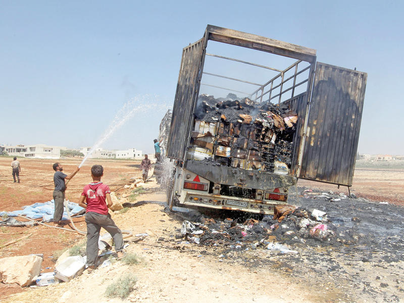 سوري يحاول إخماد نيران اشتعلت في شاحنة مساعدات استهدفتها غارة روسية على مدينة الأتارب في ريف حلب أمس الأول (رويترز)