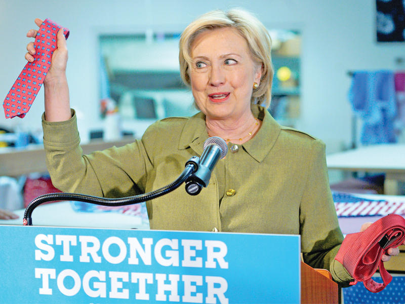 كلينتون تحمل ربطة عنق تعود لعلامة تجارية خاصة بترامب مصنوعة بالصين، وأخرى قالت إنها مصنوعة في أميركا، وذلك خلال تجمع في دنفير مساء أمس الأول (رويترز)