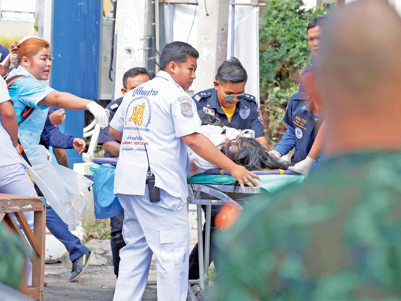 مسعفون ينقلون مصابة في انفجار قنبلة قرب برج الساعة وسط هوا هين في تايلند أمس (إي بي إيه)n