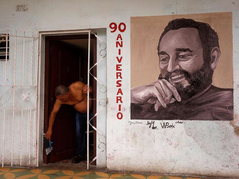 رجل ينظف منزله وتبدو صورة كاسترو على الحائط