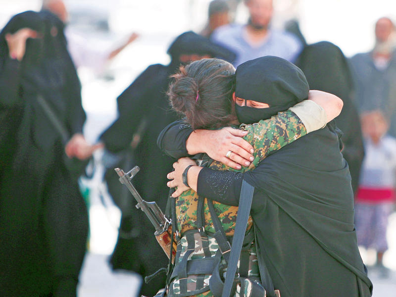 سورية منتقبة تحتضن مقاتلة كردية بعد فرار فلول «داعش» من منبج أمس الأول (رويترز)