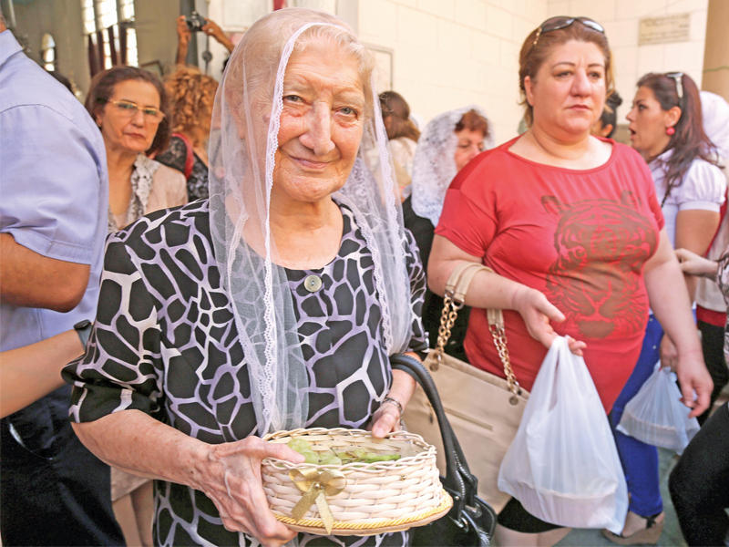 سورية من الطائفة السريانية الأرثوذكسية توزع حلوى خلال قداس في كنيسة سانت ماري بمدينة القامشلي أمس (أ ف ب)