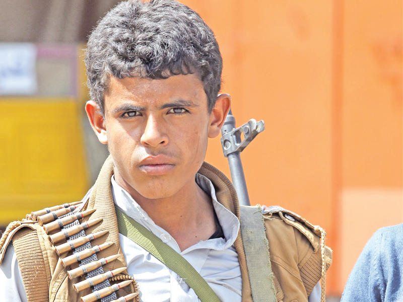 مراهق يمني يحمل بندقية خلال تجمع مؤيد للحركة الحوثية المتهمة بتجنيد أطفال للقتال في صنعاء أمس (إي بي أيه)