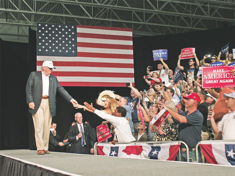 ترامب يحيي أنصاره قبل خطابه في دايمونديل بميشيغان أمس الأول (أ ف ب)