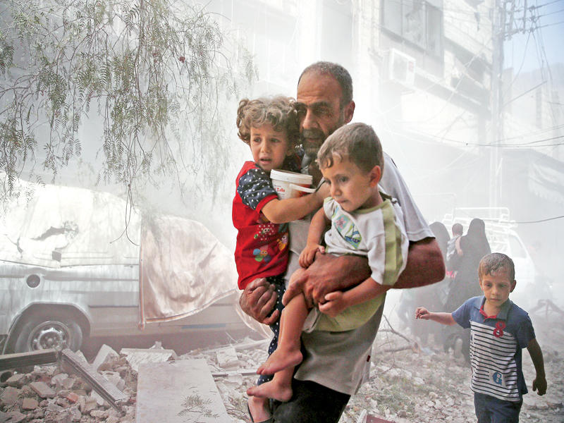 سوري يفر بأبنائه بعد غارة لطائرات النظام على دوما أمس (أ ف ب)