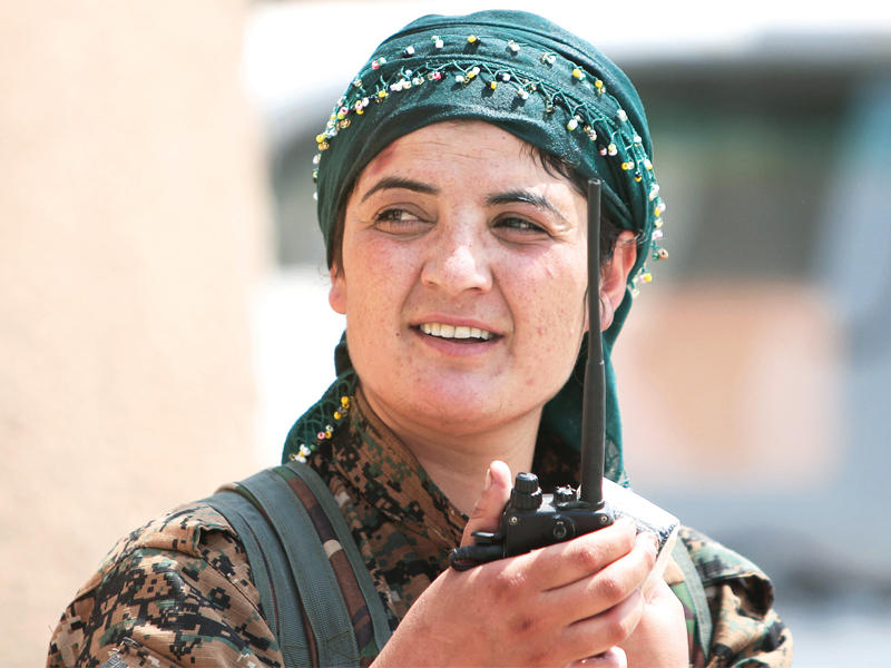 مقاتلة كردية تتقدم المواجهة ضد النظام في حي غويران بالحسكة أمس (رويترز)